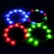 Vier bunte LED-Haustierhalsbänder in Blau, Rot, Grün und einer Mischung aus Farben, vor einem dunklen Hintergrund präsentiert.