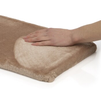 Eine Hand drückt sanft auf ein weiches, beiges Haustierbett mit plüschiger Textur, das seinen Komfort und seine Qualität zeigt.