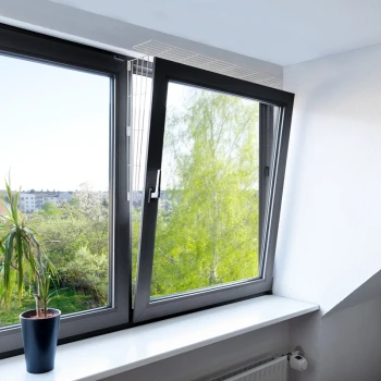 Ein modernes Fenster teilweise geöffnet, mit Blick auf grüne Bäume draußen, mit einer Topfpflanze auf der weißen Fensterbank.