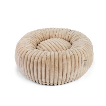 Ein plüschiges, rundes Haustierbett mit einem gerippten Design in einem sanften Beigeton, mit einem kleinen Etikett an der Seite.
