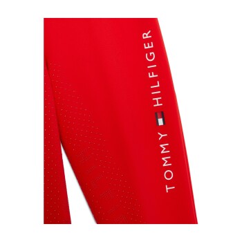 Rote Sportbekleidung mit dem weißen 'TOMMY HILFIGER'-Logo, mit einem kleinen Flaggenemblem und einem gepunkteten Texturdetail.