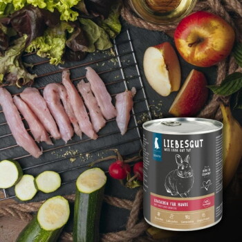 Dose LIEBESGUT „Kaninchen für Hunde“ (Kaninchen) neben rohen Kaninchenstreifen, Zucchini, Salat, Äpfeln und Radieschen.