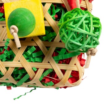 Ein geflochtener Korb, gefüllt mit grünem und rotem Papier, mit einem gelben quadratischen Block und einem grünen Ball aus dünnen Strängen.