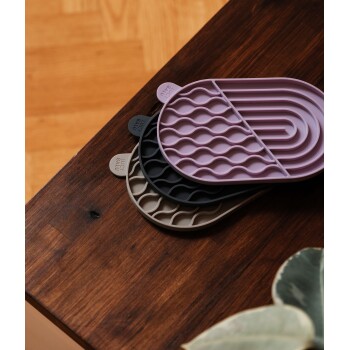 Drei Silikon-Haustierfütterungsmatten in Pink, Schwarz und Beige, die auf einer Holzoberfläche gestapelt sind, mit "LUCKY BALU" an den Rändern eingeprägt.