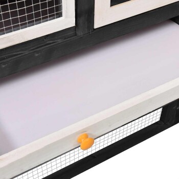 Holzhaustierkäfig mit einer herausziehbaren Schublade mit einem orangefarbenen Knopf, grau-weiße Farbgestaltung und Drahtgeflecht zur Belüftung.