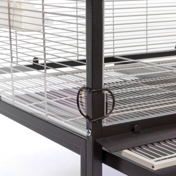 Eine Nahaufnahme eines Metallhaustierkäfigs mit einem schwarzen Rahmen, horizontalen Drahtstangen und einer herausnehmbaren Schublade am Boden.