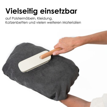 Eine Person demonstriert die einfache Reinigung eines Haustierpflegewerkzeugs mit Holzgriff. Text: "Einfache Reinigung durch Bewegung & separates Fach."