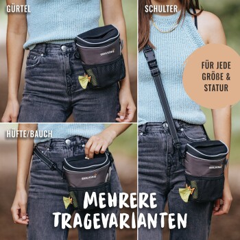 Eine Frau in einem hellblauen Oberteil hält eine 'Rydel König' Haustier-Zubehörtasche mit Gürtel-, Schulter- und Hüftoptionen, mit einer Netztasche.