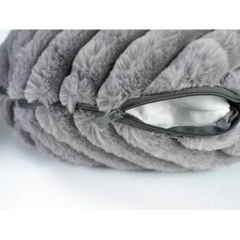 Nahaufnahme eines grauen Plüsch-Haustierbetts mit teilweise geöffnetem Reißverschluss, der weiße Innenpolsterung zeigt.