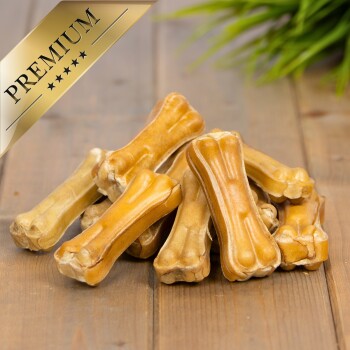 Ein Haufen hochwertiger Hundeknochenleckerlis auf einer Holzoberfläche, mit einem goldenen "PREMIUM"-Label in der oberen linken Ecke.