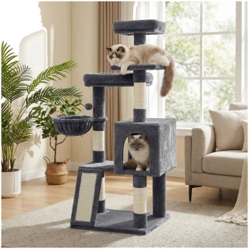 Grauer mehrstöckiger Kratzbaum mit Sisalstämmen, Hängematte und Höhle; zwei flauschige Ragdoll-Katzen in einem sonnendurchfluteten Wohnzimmer.