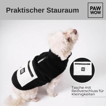 Ein kleiner weißer Hund in einer schwarzen Fleecejacke mit einem "PAW WOW"-Logo und einer Reißverschlusstasche, die mit "Praktischer Stauraum" beschriftet ist.