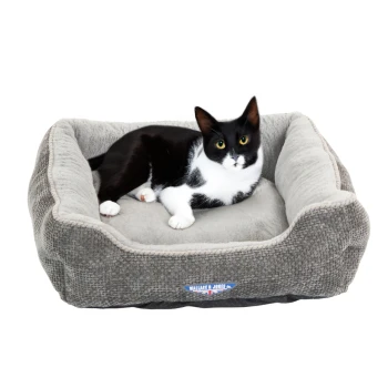 Ein gemütliches graues Katzenbett mit einem plüschigen Innenraum, mit einer schwarz-weißen Katze, die bequem darin liegt.