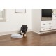 Un chien noir et blanc mangeant dans un distributeur automatique de nourriture pour animaux gris sur un sol en bois dans une cuisine moderne.