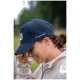 Eine Person trägt eine marineblaue Kappe mit dem Text "Hufeisenliebe" an der Seite und hält ihre Hand in der Nähe ihres Gesichts im Freien.