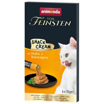Eine weiße Katze leckt sich die Lippen neben einem Teller mit cremigem Snack, mit der Verpackung "animonda vom Feinsten Snack Cream" mit Huhn und Katzenkraut.