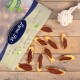 Eine Tüte Lyra-Hundeleckerlis ist teilweise geöffnet und zeigt mehrere fischförmige Snacks mit einer rötlich-braunen Füllung, die auf einer Holzoberfläche verstreut sind.
