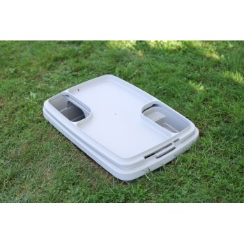 Weißer Kunststoff-Futternapf für Haustiere mit zwei Fächern, auf grünem Gras im Freien platziert.