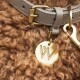 Nahaufnahme eines stilvollen Hundehalsbands mit einem goldenen Etikett mit einem "W"-Logo, das auf einem flauschigen, lockigen braunen Fell ruht.