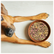 Nahaufnahme von mehrfarbigen Tierfutterpellets mit weißem Kreis, der Zutaten auf Deutsch auflistet: Weizen, Fleischmehl, Grieß, Mais, Zuckerrübenschnitzel, Mineralien, Vitamine.