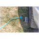 Eine Nahaufnahme eines blauen Riemens, der an einem Metallanker auf trockenem Gras befestigt ist, mit einem teilweise sichtbaren Autoreifen im Hintergrund.