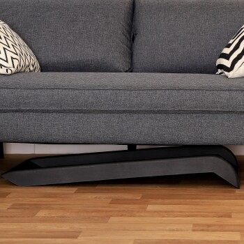 Ein modernes graues Sofa mit zwei dekorativen Kissen, eines mit einem schwarz-weißen Zickzackmuster, steht auf einem Holzboden.