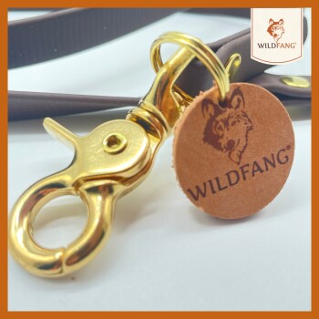 Nahaufnahme eines goldenen Metallclips, der an einer braunen Haustierleine befestigt ist, mit einem runden Lederanhänger mit dem "WILDFANG"-Logo und einer Wolfillustration.