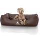 Ein hellbrauner Hund, der auf einem gemütlichen, dunkelbraunen Hundebett mit gestepptem Design liegt, mit dem Logo "KNUFFELWUFF."