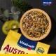 Drewniana miska z kolorowymi nasionami i ziarnami na ciemnej powierzchni, z plasterkami kiwi, zielonymi liśćmi i żółtą torbą "Vitakraft AUSTRALIA."