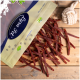 Eine Tüte mit Haustierleckereien, beschriftet "Premium Qualität", mit einem Logo, die dünne Streifen von Fleischsnacks auf eine Holzoberfläche fallen lässt, neben einem Seilspielzeug.