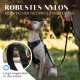 Ein Hund, der ein schwarzes Geschirr trägt, sitzt auf Gras und schaut nach oben. Der Text lautet "Robustes Nylon mit weicher Neopren-Polsterung" und "Liegt angenehm in der Hand."