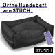 Orthopädisches Hundebett von STUCH, mit einem plüschigen grauen Kissen und schwarzem Äußeren, mit einem Etikett, das "PETA Approved Vegan" angibt.