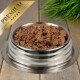 Eine Edelstahlschüssel für Haustiere, gefüllt mit hochwertigem Nassfutter für Hunde, mit einem goldenen "PREMIUM"-Label in der Ecke.