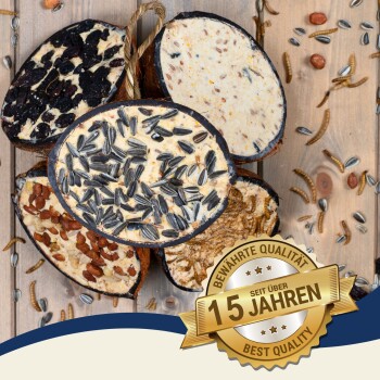 Vier runde Vogelfutterkuchen mit Samen und Nüssen auf einer Holzoberfläche, mit einem "Beste Qualität"-Abzeichen auf Deutsch.