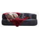 Ein großer, hellbrauner Hund und ein kleiner, flauschiger schwarzer Hund ruhen sich auf einer dunkelgrauen Couch aus, die mit einer roten Decke bedeckt ist.