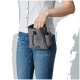 Eine Person in einem weißen Hemd und blauen Jeans hält eine graue Leckerlitasche für Haustiere mit Kordelzug und Seitentasche.