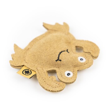 Ein süßes, plüschiges Froschspielzeug in Beige mit einem lächelnden Gesicht und weißen Augen, mit einem Etikett an der Seite.