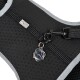 Black pet harness with a textured surface, featuring a silver logo tag and a clip for leash attachment.