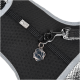 Black pet harness with a textured surface, featuring a silver logo tag and a clip for leash attachment.
