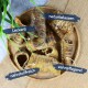 Eine Holzschale mit natürlichen Leckerlis für Haustiere, beschriftet mit "Leckerli", "naturbelassen", "nährstoffreich" und "zahnpflegend."