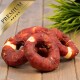 Premium-Hundeleckerlis in Ringform, mit einer fleischigen Außenseite und einem weißen Knochenzentrum, auf einer Holzoberfläche mit grünem Gras präsentiert.