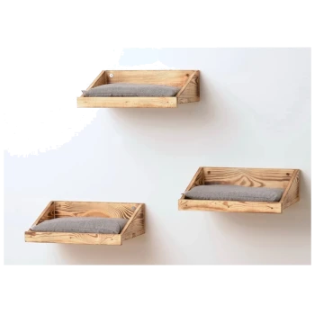 Drei hölzerne, wandmontierte Haustierbetten mit grauen Kissen, die in unterschiedlichen Höhen an einer weißen Wand angeordnet sind.