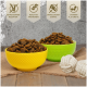 Zwei Schalen mit Futter – gelb und grün – neben weißen Seilspielzeugen. Highlights: getreidefrei, hoher Proteingehalt, kein Zuckerzusatz, Vitamine A, E, D3.