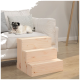 Ein Mops, der auf einem hellgrauen Sofa mit dekorativen Kissen ruht, neben einer hölzernen dreistufigen Haustiertreppe für einfachen Zugang.