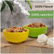 Zwei Schalen mit Tierfutter, eine gelbe mit der Aufschrift "100% Fleisch" und eine grüne mit der Aufschrift "100% natürlich", mit einem Hintergrund aus Jute und Seilspielzeugen.