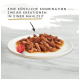 Nourriture pour animaux sur une assiette blanche avec de la viande effilochée, des morceaux rouges, une tomate cerise et du texte : "Une délicieuse combinaison de deux créations."