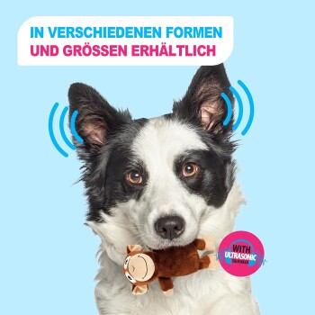 Schwarz-weißer Hund hält ein Plüschäffchen; rosa Abzeichen 'MIT ULTRASCHALL-QUITSCHER'; deutscher Text 'IN VERSCHIEDENEN FORMEN UND GRÖSSEN ERHÄLTLICH' auf blauem Hintergrund.