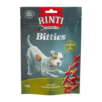 Die Verpackung von Rinti Bitties Hundeleckerlis zeigt einen verspielten Hund, beschriftet mit "Ohne Zucker" und "mit Ananas & Kiwi."