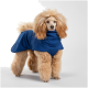 Ein flauschiger Hund trägt einen blauen Haustiermantel, steht vor einem weißen Hintergrund und zeigt das Design und die Passform des Mantels.