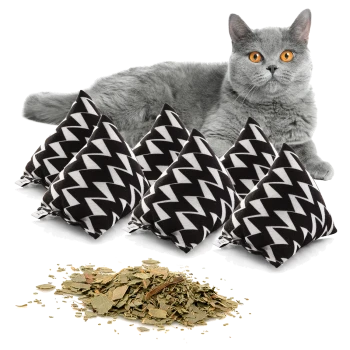 Eine graue Katze mit leuchtend orangefarbenen Augen sitzt hinter fünf schwarz-weißen Katzenminzkissen mit Zickzack-Muster, mit getrockneter Katzenminze, die davor verstreut ist.